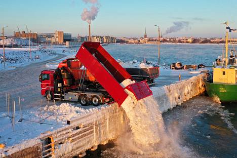 Kuorma-autot kaatavat lunta mereen Hernesaaressa tammikuussa 2021.