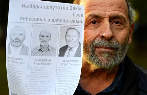 Oikea Boris Višnevski esittelee printtiä vaalien ehdokaslistasta, jossa hän (oikealla) poseeraa kahden samannäköisen kaimansa kanssa.