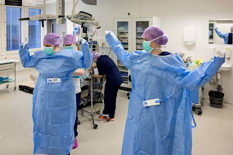 Instrumenttihoitajina toimivat opiskelijat pukeutuvat leikkaus­sali­vaatteisiin. Avustava hoitaja Jasmin Mäenpää toimii apurina.
