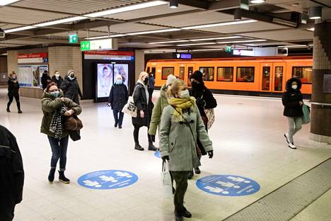 Matkustajat käyttivät kasvomaskeja metroasemalla Helsingissä maaliskuussa 2021.