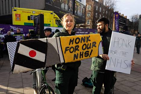 Ensihoitaja piteli kylttiä Britannian julkisen terveydenhuoltojärjestelmä NHS:n tueksi Waterloon ambulanssiaseman edessä Lontoossa keskiviikkona.