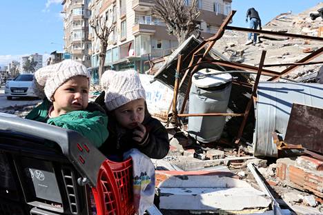 Pipopäiset lapset seurasivat ostoskärryssä pelastustöitä talon raunioilla Turkin Hatayssa keskiviikkona.