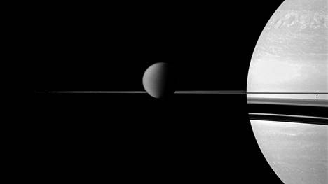 Saturnuksen kuista suurin on Titan, joka näkyy kuvassa keskellä. Jääpintainen Enceladus erottuu oikealla rengastason alla. Kuvan otti Cassini-luotain vuonna 2011. 