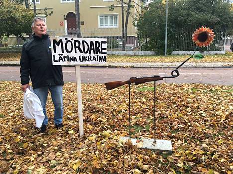 Kuvassa Ukrainaplatsenin aktiiveihin kuuluva Mosse Wallén ja taideteos, jonka poliisi takavarikoi aiemmin tänä vuonna. Taustalla näkyy Maarianhaminassa sijaitseva Venäjän konsulaatti. Wallénin mukaan teos on rauhansymboli.