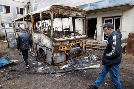Miehet kävelevät raketin tuhoaman koulubussin ohi Makarivin keskustassa. 