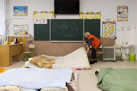 School principal Irena Zhyk prepared mattresses at a refugee accommodation center in Lviv on Saturday.  The painting reads “Slava Ukraina” or “Glory to Ukraine”. 