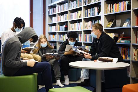 Lukutaidon opettaja Aleksi Nissinen lukee yhteiskuntaoppia yhdeksäsluokkalaisten kanssa Itäkeskuksen peruskoulun kirjastossa.