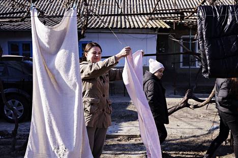 Maria Burlaku (vas.) ripustaaa pyykkiä Ljuba Prodanin pihassa. Tudoralainen Ljuba Prodan majoittaa kotonaan kahta kolmihenkistä perhettä, jotka pakenivat Harkovasta.