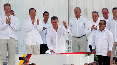 Kolumbian presidentti Juan Manuel Santos esitteli Cartagenassa luodista tehtyä kynää ennen kuin allekirjoitti sopimuksen Farc-järjestön johtajan Timochenkon (oik.) kanssa. Osanottajat olivat pukeutuneet tunteikkaassa ulkoilmaseremoniassa kokovalkoisiin asuihin.