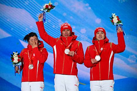 Chinese freestyle skiing team Xu Mengtao, Jia Zongyang and Qi Guangpu celebrate their silver medals on the podium.  The trio are wearing racing outfits made by Anta Sports.