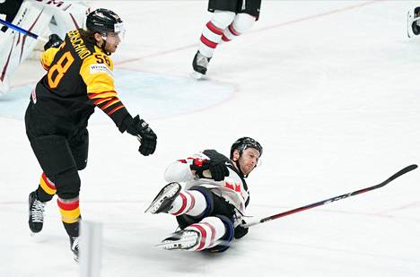 Kanadalaispelaaja kellahtaa jäähän Saksan  Markus Eisenschmidin edessä joukkueiden välisessä ottelussa maanantai-iltana.
