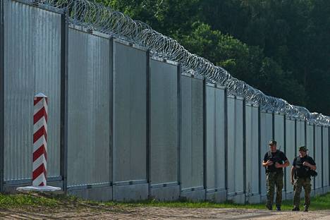 Puolan rajavartijat kulkivat vastavalmistuneen muurin edustalla lähellä Nowdzielin kylää 29. kesäkuuta 2022. 