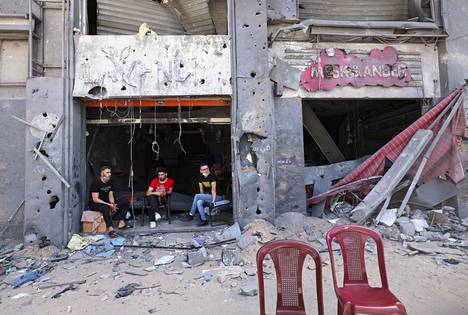 Palestiinalaiset istuvat iskuissa tuhoutuneen kauppansa edessä Gazassa 22. toukokuuta.