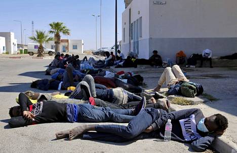 Tunisian armeijan pelastamat siirtolaiset lepäsivät satamassa Ben Gardanen kaupungissa, lähellä Libyan rajaa Kaakkois-Tunisiassa 11. kesäkuuta 2021. He olivat yrittäneet ylittää Välimeren veneellä. Tunisia ja Libya ovat keskeisiä lähtöpaikkoja Eurooppaan yrittäville siirtolaisille.