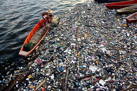 Kalastaja tyhjentää pyydystään muoviroskan täyttämässä vedessä Bulcanissa Filippiineillä.