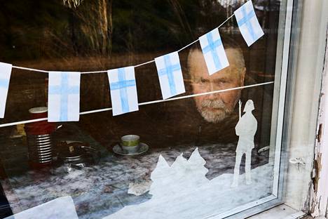 Raerinteiden kodin ikkunassa ovat yhä lastenlasten kanssa itsenäisyyspäiväksi tehdyt koristeet. Ikkunasta ulos katsoo Jussi Raerinne.