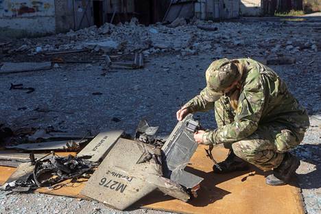 Ukrainalaissotilas ja iranilaisvalmisteisen Shahed-136-lennokin jäänteitä Harkovassa Ukrainassa lokakuun alussa. Venäläiset olivat merkinneet lennokin omilla tunnuksillaan.