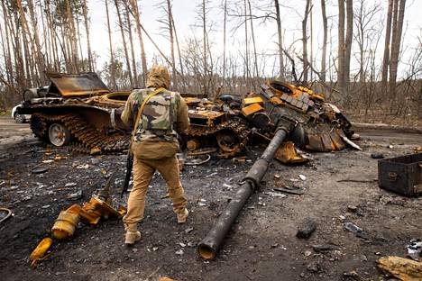 Ukrainalaissotilas tutki tuhoutunutta venäläistä panssarivaunua Butšassa lähellä Kiovaa maanantaina.