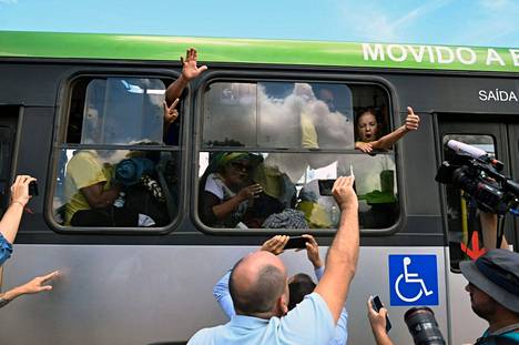 Joukko Bolsonaron pidätettyjä kannattajia viittoi bussista lähtiessään liittovaltion poliisin päämajalta tiistaina.