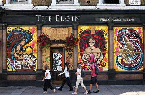 Ihmiset kävelivät Notting Hill Carnival -tapahtuman takia vanerilla suojatun pubin ohitse lauantaina Lontoossa. 