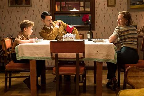 Jojo (Roman Griffin Davis), Adolf (Taika Waititi) ja Rosie (Scarlett Johansson) yhteisen pöydän ääressä.