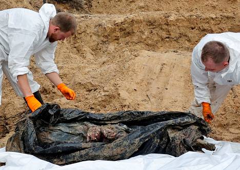 Tutkijat tarkastelivat ruumista, jonka kädet oli sidottu selän taakse.
