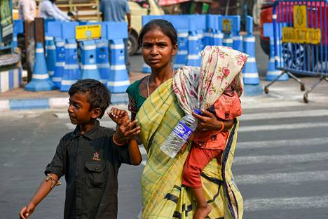 Intialaisnainen on suojannut pienen lapsensa sarillaan suojellakseen häntä iltapäivän helleaallolta Kalkutassa tiistaina.