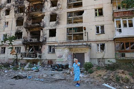 Paikallinen nainen seisoo tuhoutuneen kerrostalon edessä Severodonetskissa.