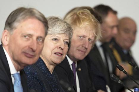 Kovan brexitin kannattajat toivovat potkuja valtiovarainministeri Philip Hammondille (vas.). Hänen vierellään pääministeri Theresa May sekä brexit-leirin kärkihahmoihin kuuluva ulkoministeri Boris Johnson.