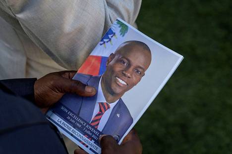 Hautajaisvieras piteli Haitin murhatun presidentin  Jovenel Moïsen  kuvaa käsissään heinäkuussa 2021.