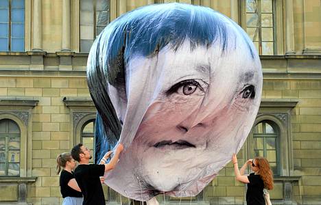 Aktivistit täyttivät Angela Merkelin kuvalla koristettua ilmapalloa Münchenissä perjantaina. Aktivistit protestoivat viikonloppuna alkavaa Baijerissa järjestettävää G7-maiden huippukokousta.