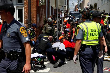 Pelastustyöntekijät auttoivat väkijoukkoon ajaneen auton alle jäänyttä Charlottesvillessä.