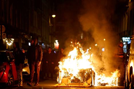 Jalankulkijat kävelivät mielenosoituksissa tuleen sytytetyn roskiksen ohi Pariisissa 30. maaliskuuta.
