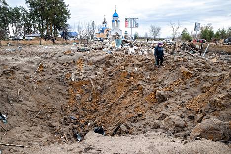 Maria Kšyžovska seisoo puutarhaansa pudonneen venäläisen lentopommin räjäyttämässä kuopassa. Hänen takanaan oleva rojukasa on se, mitä hänen kotitalostaan jäi jäljelle. 
