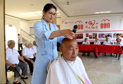Yang Ruimei leikkaa vanhainkodin asukkaan hiuksia Weixianin kaupungissa Kiinassa. Myös Kiinassa on iso hoivahaaste.
