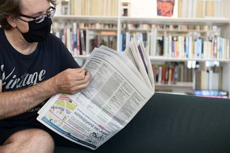 Sanomalehden lukija maski kasvoillaan keskustakirjasto Oodissa Helsingissä elokuussa 2020.