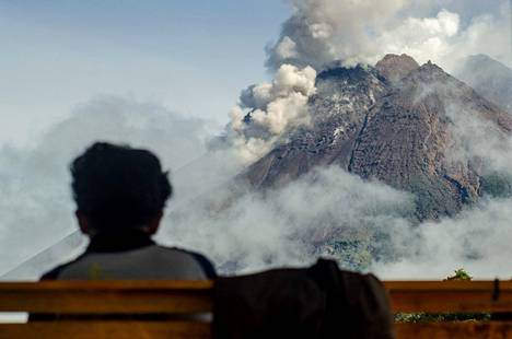 Kyläläinen katseli penkiltä tulivuori Merapia Slemanissa Indonesiassa torstaina. Merapi on Indonesian aktiivisin tulivuori.