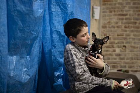 Andrii, 10, koiran kanssa lvivilaisen kirkon ruokalassa.