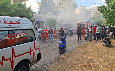 Emergency vehicles and smoke outside a mobile phone shop in Sidon, southern Lebanon, on Wednesday.