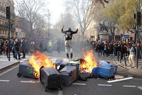 Mielenosoittajan hyppy palavien roskalaatikoiden päällä Toulousessa torstaina. 