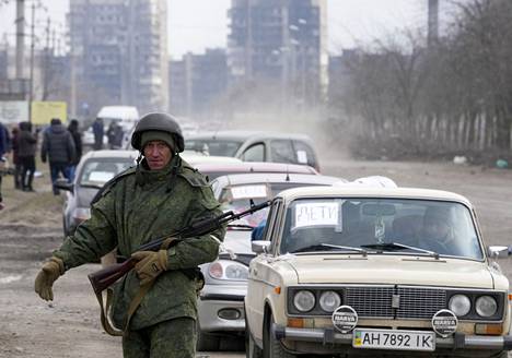 Separatistijoukkojen sotilas tarkkaili Mariupolista pois suuntaavaa autojonoa sunnuntaina. Tuulilasin lapussa lukee, että kyydissä on lapsia.