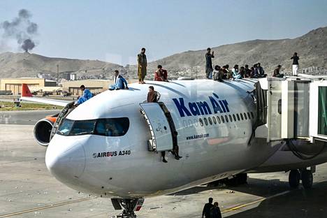 Afganistanilaiset kiipesivät lentokoneen päälle maanantaina Kabulin lentokentällä. 