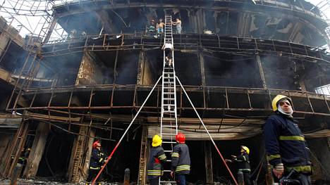 Palomiehet tutkivat raunioita Karradan kauppa- ja markkina-alueella Baghdadissa 3. heinäkuuta.