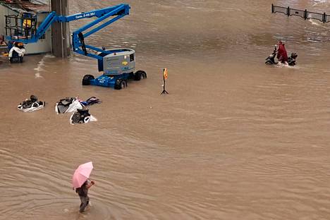 Ihmiset pyrkivät eteenpäin tulvavedessä Zhengzhoussa tiistaina 20. heinäkuuta.