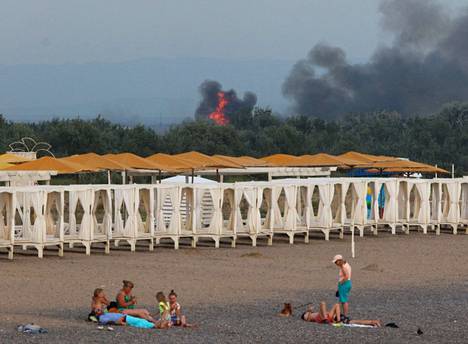Ihmiset viettivät tiistai-iltapäivänä aikaa hiekkarannalla Novofedorivkassa Krimin niemimaalla takana näkyvistä lentokenttäiskun savupilvistä huolimatta.