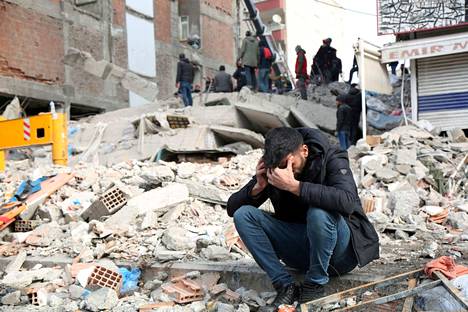 Mies istuu romahtaneen rakennuksen raunioilla Diyarbakırissa 8. helmikuuta.