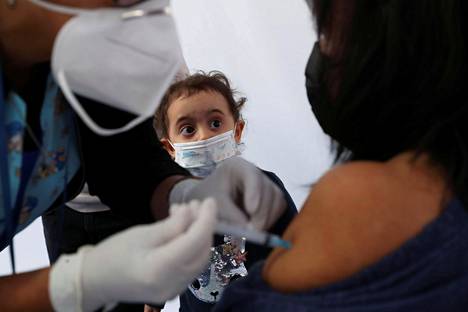 Lapsi katsoo, kun hänen vanhempansa sai koronavirusrokotteen Chilen Santiagossa maaliskuussa.