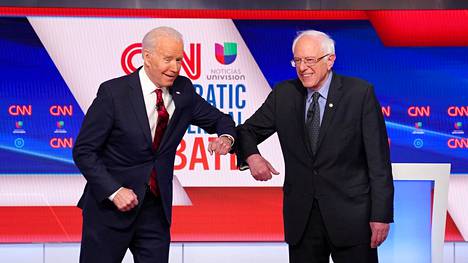 Demokraattien presidenttiehdokkaat Joe Biden ja Bernie Sanders tervehtivät toisiaan kyynärpäätervehdyksellä sunnuntain vaaliväittelyssä.