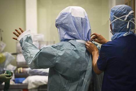 Hoitaja pukee kirurgille suojavaatteita Kainuun keskussairaalassa.