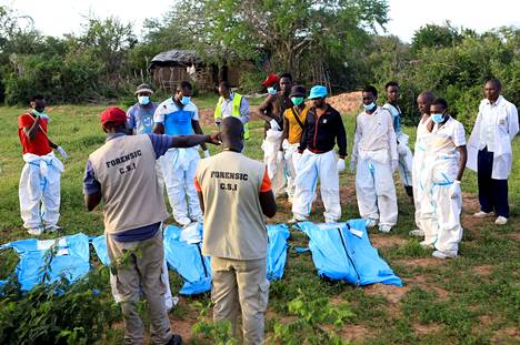 Rikosteknisiä tutkijoita ja poliisiviranomaisia haudoista nostettujen ruumiiden äärellä Shakaholan metsässä Keniassa 11. toukokuuta.